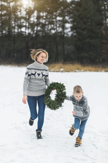 Glücklicher Familienmutter- und -kindsohn in Jeans und gestrickten Pullovern, Laufen und Spaß haben