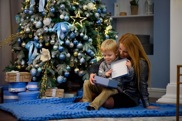 Glücklicher Familienmutter- und kleiner Babysohn, der nach Hause an den Weihnachtsferien spielt. Neujahrsfeiertage