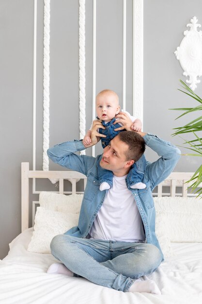 Glücklicher familienvater, der zu hause mit dem baby auf dem bett spielt, vatertagskonzept oder glückliche vaterschaft