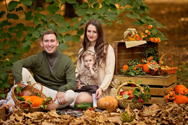 Glücklicher Familienvater, Mutter, kleine Tochter beim Herbstpicknick mit Kürbis und Äpfeln