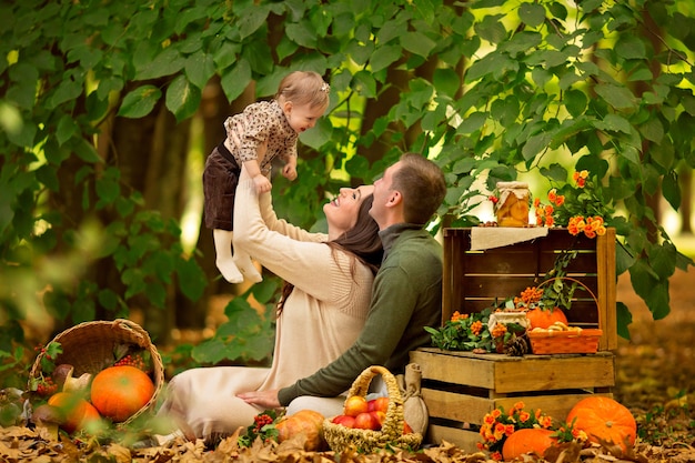 Glücklicher Familienvater, Mutter, kleine Tochter beim Herbstpicknick mit Kürbis und Äpfeln