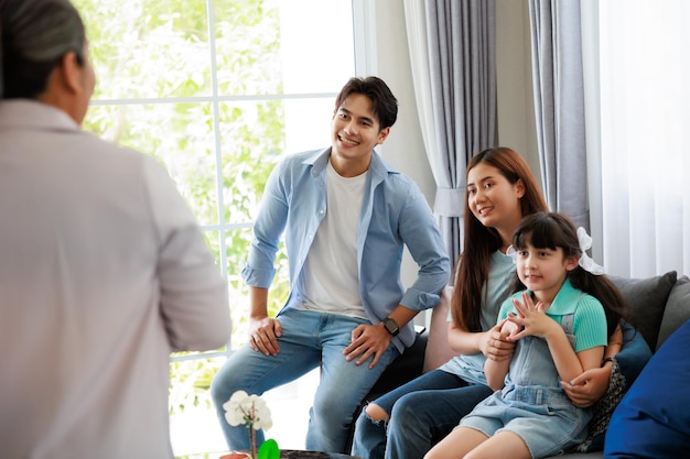 Glücklicher Familienvater, Mutter und Tochter hören sorgfältig zu, wie die ältere Verkaufsagentur das Hausdetail im Wohnzimmer präsentiert