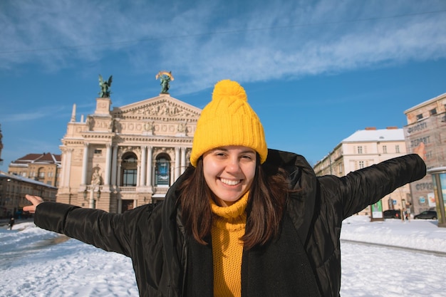 Glücklicher Frauenreisender vor dem Operngebäude in der Wintersaison der Stadt Lemberg verschneite Stadt