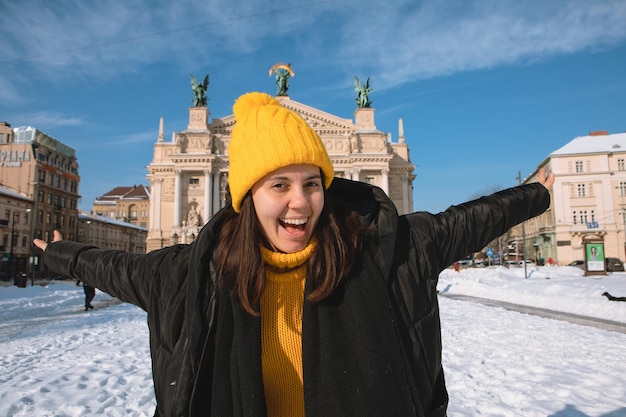 Glücklicher Frauenreisender vor dem Operngebäude in der Wintersaison der Stadt Lemberg verschneite Stadt