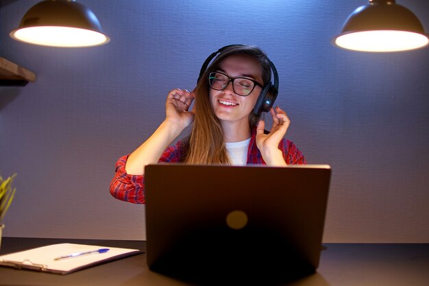 Glücklicher freudiger zufriedener Musikliebhaber der Frau in kabellosen Kopfhörern, die Musik online mit einem Laptop genießen und hören