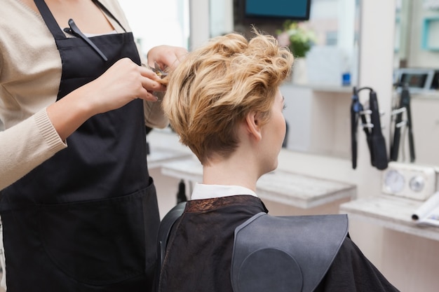 Glücklicher Friseur, der ein Kundenhaar schneidet