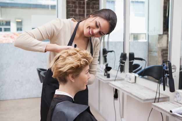 Glücklicher Friseur, der ein Kundenhaar schneidet