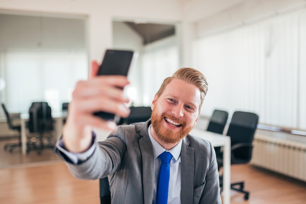 Glücklicher Geschäftsmann, der selfie bei der Arbeit nimmt.