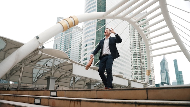 Glücklicher Geschäftsmann geht die Treppe hinunter und bewegt sich zu Musik von Kopfhörern urbane