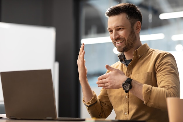 Glücklicher Geschäftsmann Videoanrufe per Laptop im modernen Büro