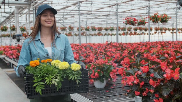 Glücklicher Gewerbeschäftiger trägt Schachteln voller Blumen, lächelt und ist eine glückliche Frau mit Blumen, die wächst.