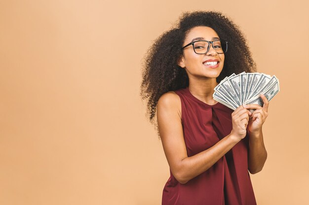 Glücklicher Gewinner. Porträt der erfolgreichen Frau 20s mit Afro-Frisur, die viel Geld hält