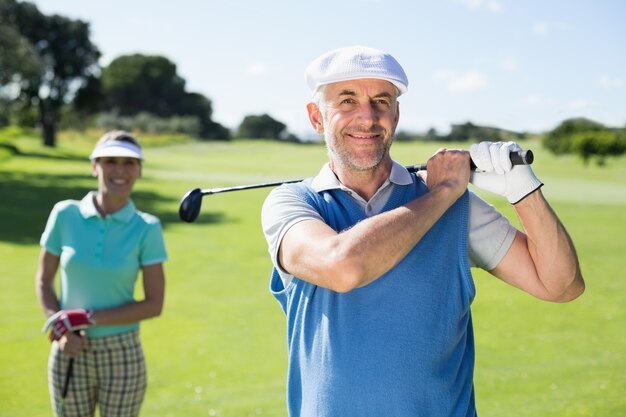 Glücklicher Golfspieler, der weg mit Partner hinter ihm abschlägt