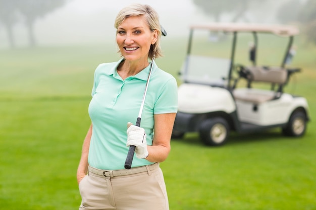 Glücklicher Golfspieler mit Golfbuggy hinten