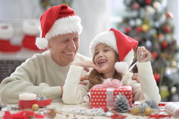 glücklicher Großvater und Kind in Weihnachtsmützen, die sich auf Weihnachten vorbereiten