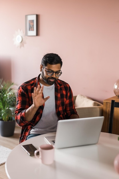 Glücklicher indischer freiberufler oder unternehmer haben videokonferenzgespräche, die remote online zu hause arbeiten, videoanruf und diversitätskonzept