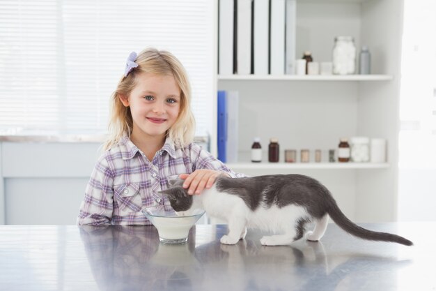 Glücklicher Inhaber, der ihre Trinkmilch der Katze streichelt