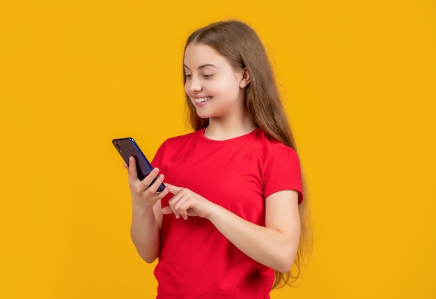 Glücklicher jugendlich Kinderchat auf Smartphone auf gelbem Hintergrund