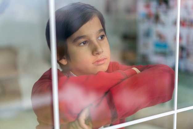 Glücklicher Junge hinter Fensterglas