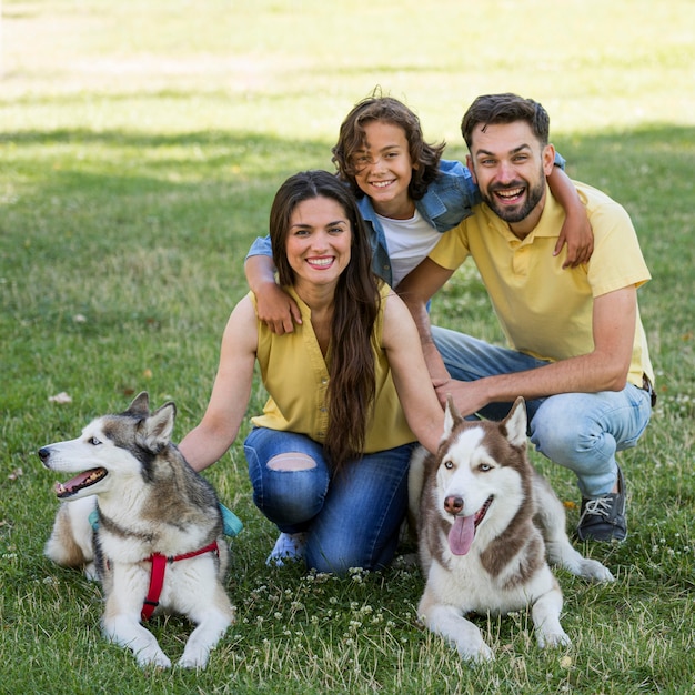 Foto glücklicher junge mit hunden und eltern, die zusammen am park aufwerfen