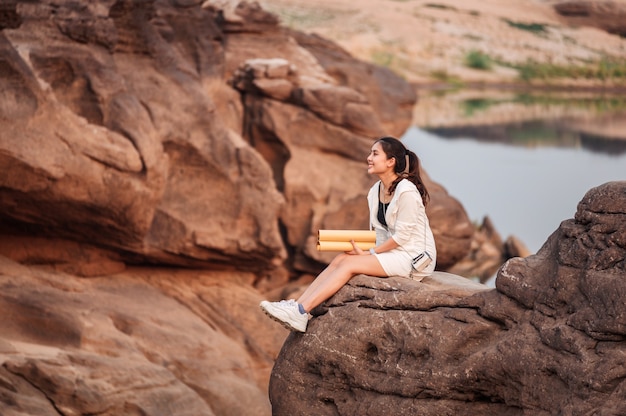 Glücklicher junger asiatischer Frauenreisender mit Papierkarte auf Felsenklippe im Grand Canyon von Thailand