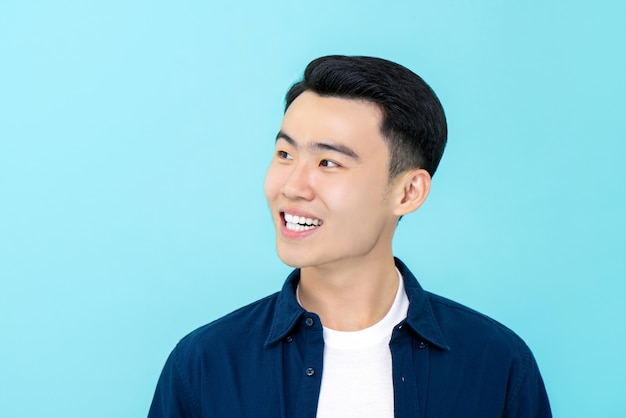 Glücklicher junger asiatischer Mann, der seitlich lächelt und schaut