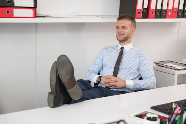 Glücklicher junger Geschäftsmann arbeitet im modernen Büro am Computer