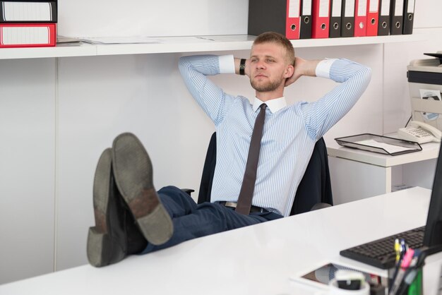 Glücklicher junger Geschäftsmann arbeitet im modernen Büro am Computer