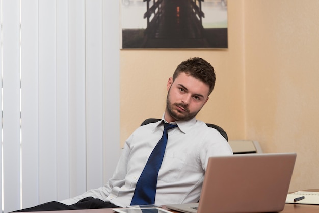 Glücklicher junger Geschäftsmann arbeitet im modernen Büro am Computer