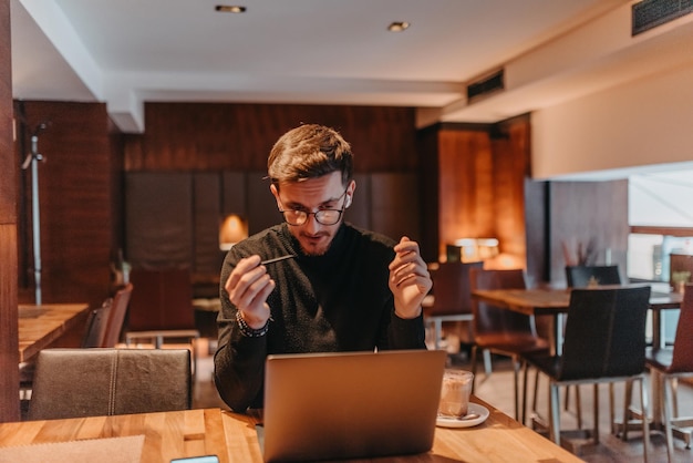 Glücklicher junger Geschäftsmann, der in einem Café an einem Laptop arbeitet