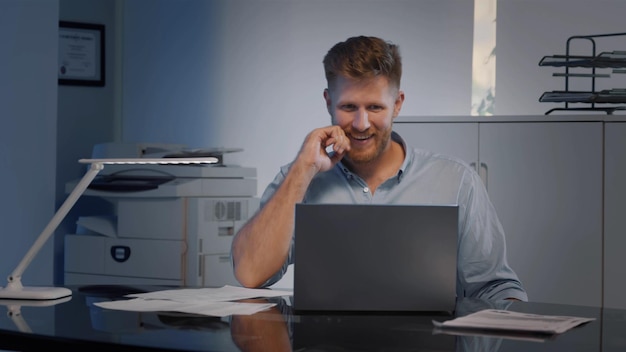 Glücklicher junger Geschäftsmann im Hemd mit Laptop, begeistert von guten Nachrichten im Internet