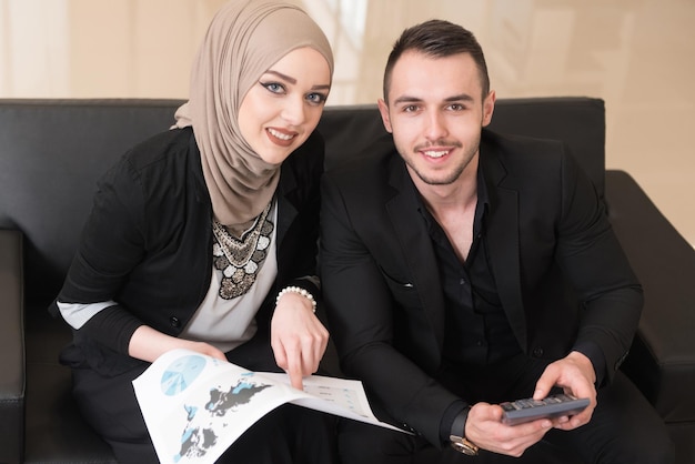Glücklicher junger Geschäftsmann und muslimische Frau arbeiten im modernen Büro am Computer
