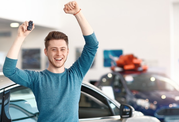 Glücklicher junger männlicher Gewinner im Autohaus