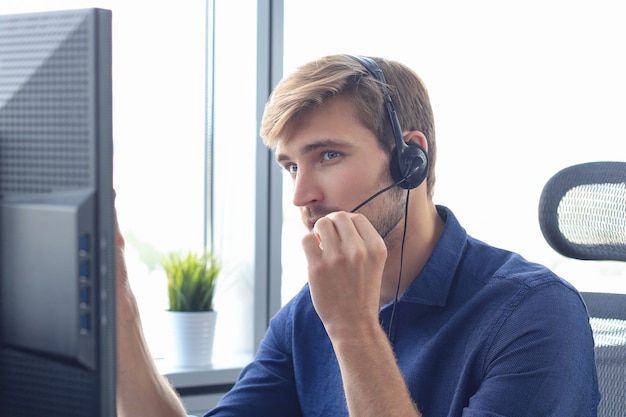 Glücklicher junger männlicher Kundenbetreuer, der im Büro arbeitet.