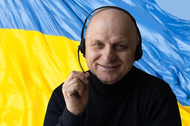 Glücklicher junger Mann auf dem Hintergrund der Flagge der Ukraine