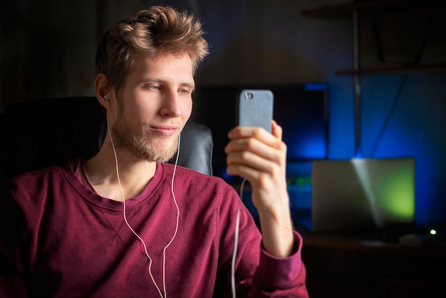 Glücklicher junger Mann benutzt Kopfhörer und hört Musik b