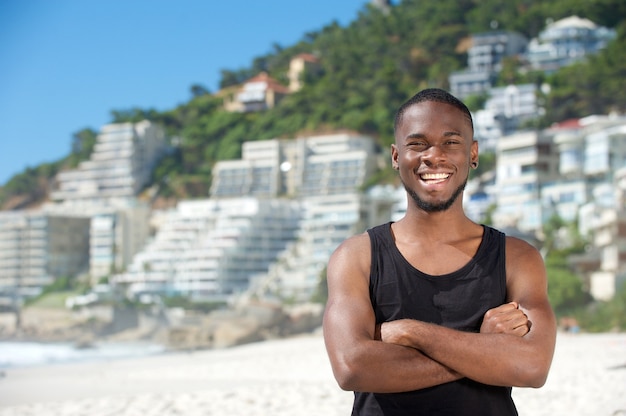 Glücklicher junger Mann, der am Strand lächelt