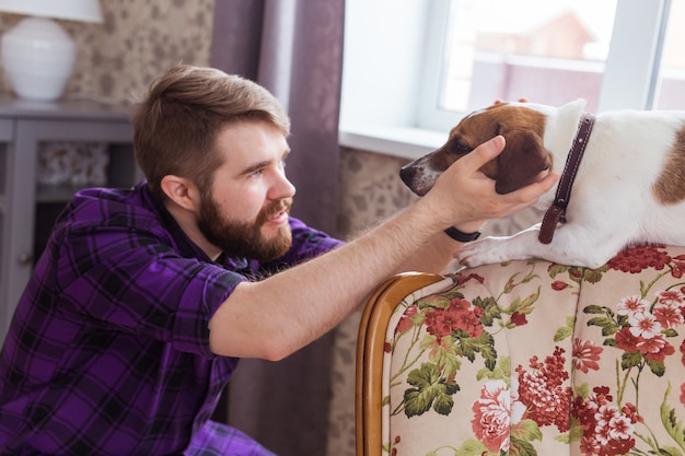 Glücklicher junger Mann, der mit seinem Hund zu Hause sitzt