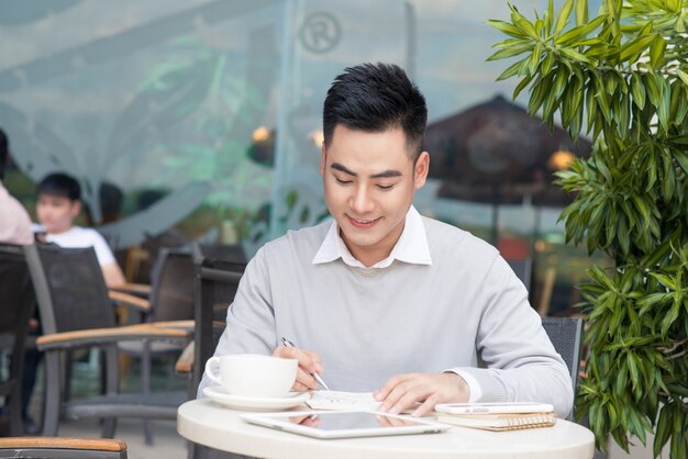 Glücklicher junger Mann, der während der Kaffeepause in der Café-Bar an einem Laptop arbeitet?