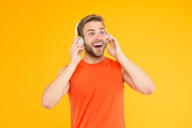 Glücklicher junger Mann in Sportkleidung trägt moderne Kopfhörer, die Musik hören, während er Sportmusik trainiert