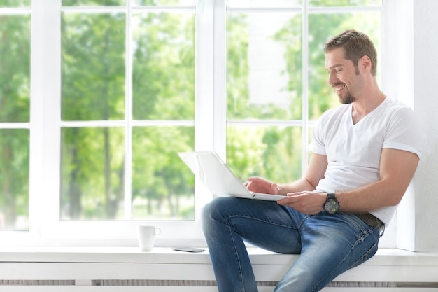 Glücklicher junger Mann mit Computerlaptop zu Hause