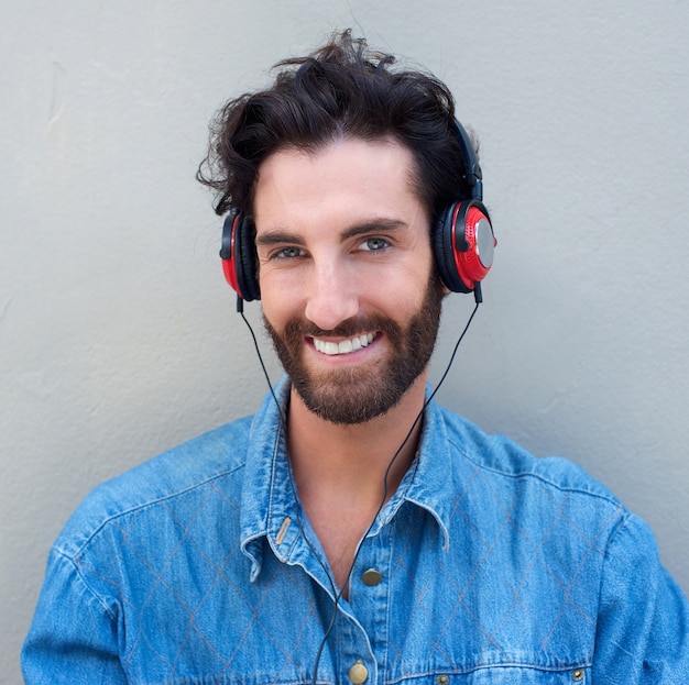 glücklicher junger Mann mit dem Bart, der Musik mit Kopfhörern hört
