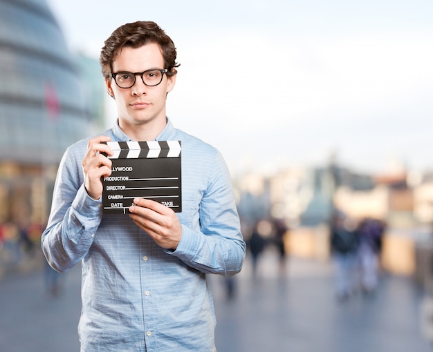 Glücklicher junger Mann mit einem clapperboard