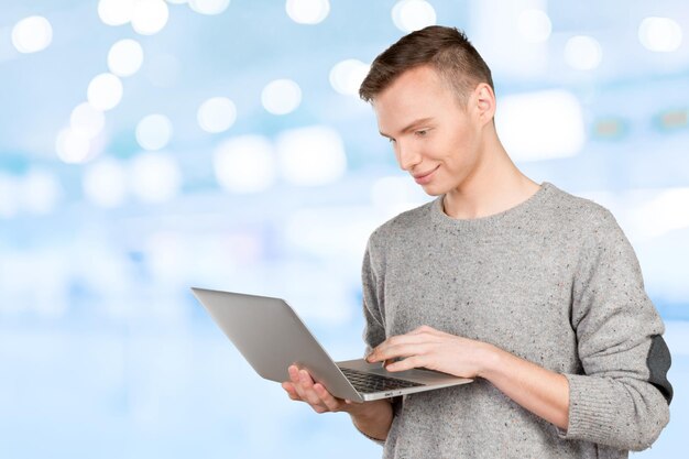 Glücklicher junger Mann mit Laptop