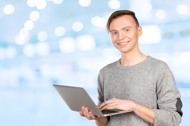 Glücklicher junger Mann mit Laptop