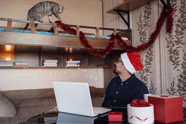 Glücklicher junger Mann mit lustiger Katze zu Hause Weihnachtsgeschenkboxen