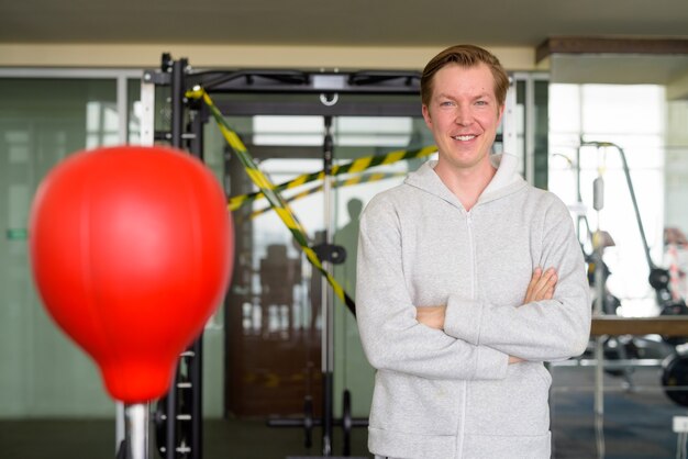 Glücklicher junger Mann mit verschränkten Armen bereit zum Boxen im Fitnessstudio