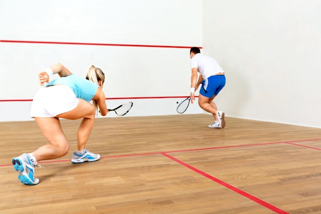 Glücklicher junger Mann und Frau, die Squash spielen