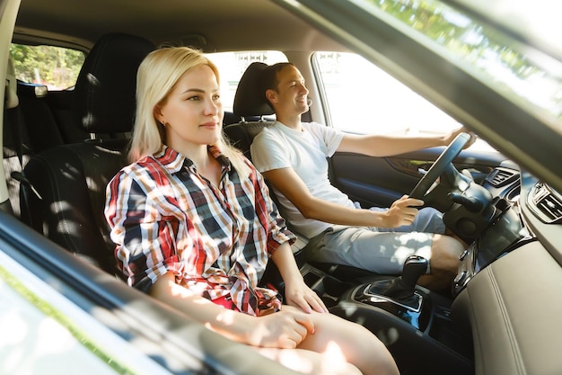 Glücklicher junger Mann und Frau in einem Auto, die an einem Sommertag einen Roadtrip genießen.