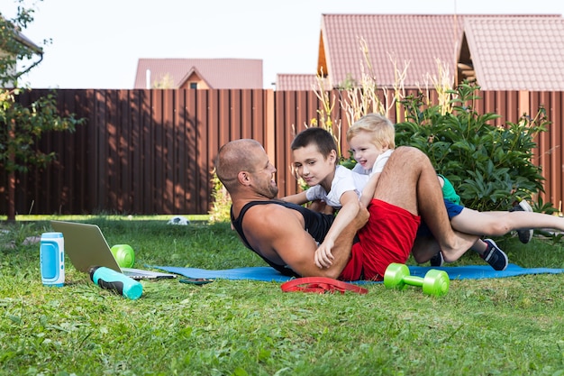 Glücklicher junger Papa spielt mit ihrem Baby auf einem grünen Rasen. Konzept einer glücklichen Familie. Vatertag. Papa und Söhne haben gemeinsame Aktivitäten in den Ferien im Hinterhof